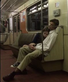 two people sitting on a subway train next to each other