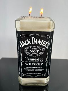 a jack daniels candle sitting on top of a black table next to a white wall