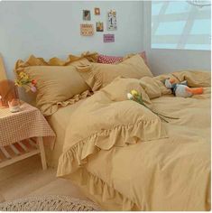 a bed with ruffled sheets and pillows in a room next to a small table