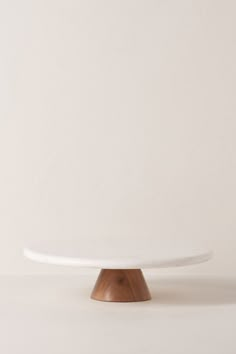 a white cake plate sitting on top of a wooden stand