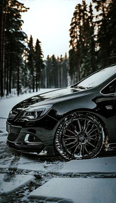 a black car parked in the snow near some trees