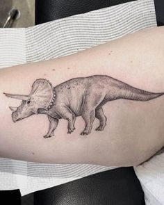 a small dinosaur tattoo on the arm