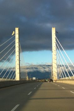 the bridge is very tall and has many cables on each side, with mountains in the background