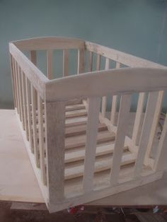 a baby crib sitting on top of a wooden table next to a wall and floor