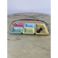 four different colored dishes sitting on top of a marble counter next to a metal rack