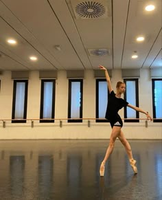 a young ballerina is practicing in an empty room with lots of lights on the ceiling