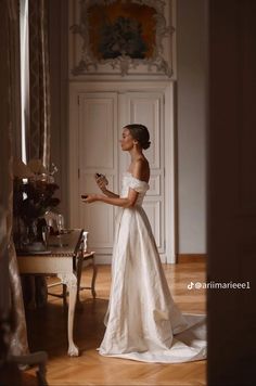 a woman in a white dress is standing by a table and looking up at something