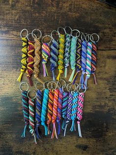 many different colored bracelets are arranged on a wooden table with one keychain in the middle