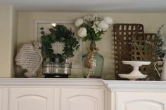 a shelf with vases, flowers and other items on it's mantle top