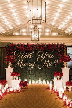 a wedding ceremony with candles and flowers on the aisle, which says will you marry me?