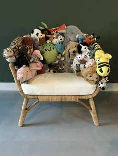 a chair filled with stuffed animals sitting on top of a floor next to a wall