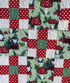 a red and white patchwork quilt with gnomes in the forest on it's side