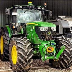 two large tractors parked next to each other in front of a building with another tractor behind them