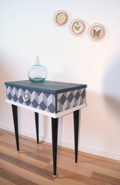 a black and white table sitting on top of a hard wood floor next to a wall