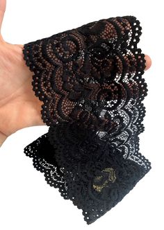 a hand is holding two pieces of black lacy fabric with gold sequins on it