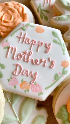 a mother's day cookie with frosting and flowers on it sitting next to other decorated cookies