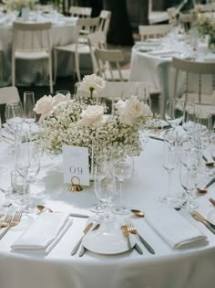 the table is set with white flowers and place settings for guests to sit down at