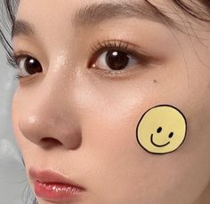 a woman with a smiley face sticker on her cheek