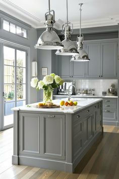 a large kitchen with gray cabinets and white counter tops, an island in the middle