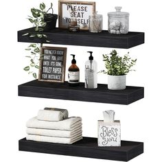 three black shelves with towels, plants and other items on top of them in front of a white background