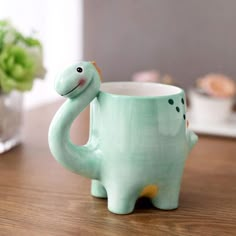 a ceramic dinosaur mug sitting on top of a wooden table