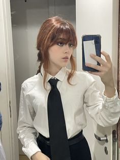 a woman in a white shirt and black tie taking a selfie with her cell phone