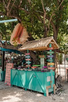 an outdoor stand with lots of items on display under a tree in front of a building