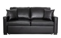 a black leather couch with two pillows on it's back and one arm facing the camera