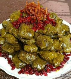 a white plate topped with stuffed grape leaves and cranberries