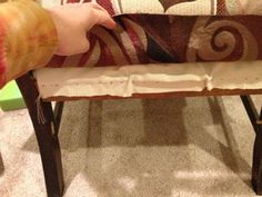 a child is holding onto a bench made out of wood and fabric, with their hand on the seat