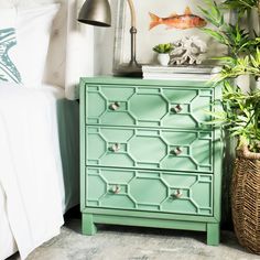 a green chest of drawers next to a lamp and potted plant in a bedroom