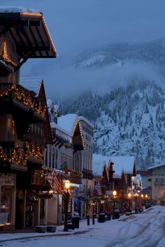 the town is covered in snow and lit up with christmas lights on it's buildings