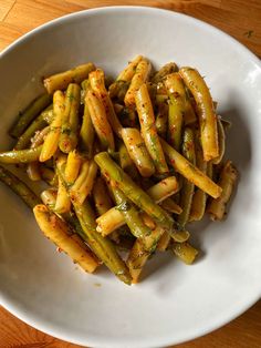 a white bowl filled with green beans on top of a wooden table