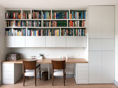 a dining room table with two chairs and bookshelves behind it