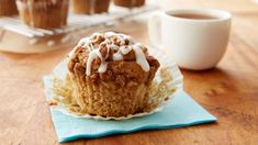 a muffin sitting on top of a blue napkin next to a cup of coffee