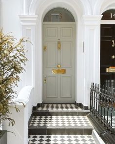 an entry way with black and white checkered tile on the floor next to a potted plant