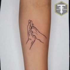 two hands holding each other in the middle of a tattoo on someone's arm