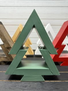 three wooden christmas trees sitting next to each other on top of a black table with red, green and yellow frames