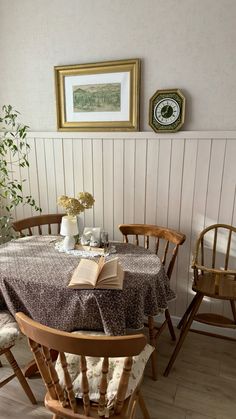 a dining room table with two chairs and an open book on top of the table