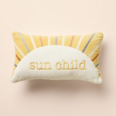 a sun child pillow on a pink wall