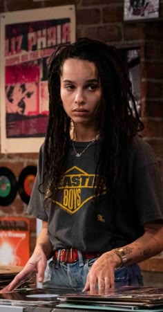 a young man with dreadlocks standing in front of a record player and looking at the camera