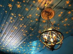 a chandelier hanging from the ceiling with stars painted on it and lights shining