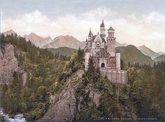 an old castle sitting on top of a mountain surrounded by trees and mountains in the background