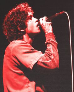 a woman with curly hair singing into a microphone