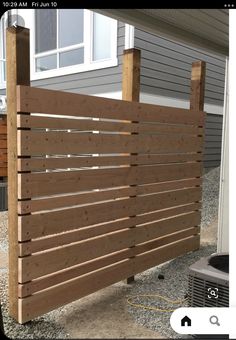 a wooden slatted fence in front of a house with an air conditioner