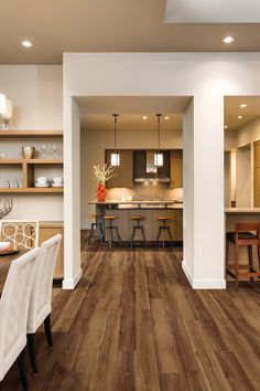 a dining room and kitchen area with wood flooring in an open concept home setting