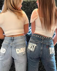 two women standing next to each other wearing jeans with the words best day written on them