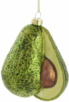 an avocado ornament hanging from a chain on a white background with green speckles