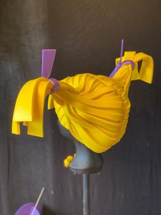 there is a yellow dress on top of a mannequin's head with purple hair