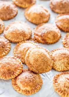 several small pastries on a baking sheet with powdered sugar over the top and bottom